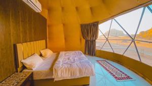 a bedroom with a bed and a large window at Desert Eyes Camp in Wadi Rum
