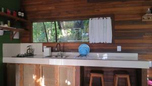 uma cozinha com um balcão com um lavatório e uma janela em Cabanas sítio Ancestral em Morretes