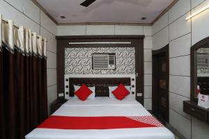 um quarto com uma cama grande e almofadas vermelhas em OYO Hotel Vanshika em Agra