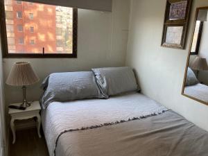ein kleines Schlafzimmer mit einem Bett und einem Fenster in der Unterkunft Habitación Metro Escuela Militar in Santiago