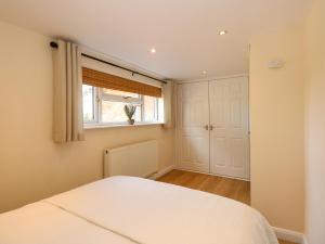 1 dormitorio con cama blanca y ventana en Meadow Cottage en Skegness