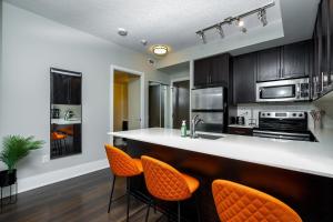 a kitchen with black cabinets and orange bar stools at Condo in the heart of Downtown Toronto! in Toronto