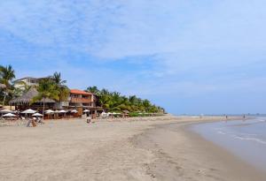 a beach with umbrellas and people on the sand at Fundo Matufa Mancora in Canoas De Punta Sal