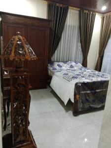 ein Schlafzimmer mit einem Bett und einem Tisch mit einer Lampe in der Unterkunft Mbah Oden Homestay Borobudur in Mendut