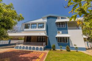 una casa azul y blanca con patio en The Rise - Poolside Villa, en Gurpur