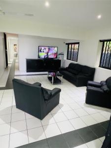 a living room with couches and a flat screen tv at Breath of Fresh air Suva Fiji in Suva