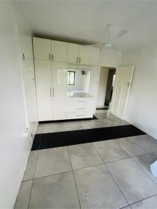 a kitchen with white cabinets and a black and white tile floor at Breath of Fresh air Suva Fiji in Suva