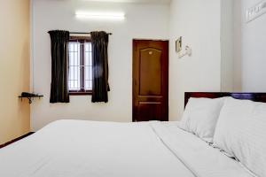 a bedroom with a white bed and a window at Flagship Airport Inn in Irugūr