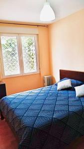 a bedroom with a blue bed with two windows at Acogedor piso en Puertollano in Puertollano
