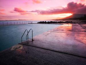 una puesta de sol sobre un cuerpo de agua con un muelle en Blissful Beach Escape in Balgownie en Balgownie