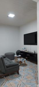 sala de estar con sofá y TV de pantalla plana en Quarto em casa familiar. en Porto Velho