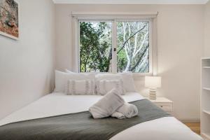 ein weißes Schlafzimmer mit einem großen Bett und einem Fenster in der Unterkunft Sahaja Cottage - WENTWORTH FALLS in Wentworth Falls