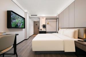 a bedroom with a white bed and a tv on a wall at Atour X Hotel Ningbo Railway Station North Square in Ningbo