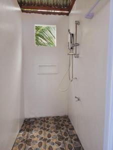 baño con ducha y suelo de baldosa. en HYD Hostel Moalboal, en Moalboal