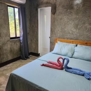 2 toallas rojas y azules en una cama en HYD Hostel Moalboal, en Moalboal