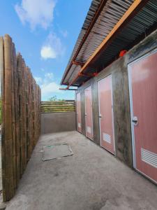 una fila de puestos con puertas rosas y una valla en HYD Hostel Moalboal, en Moalboal
