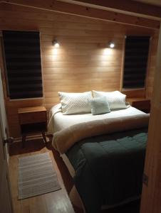 una camera con un letto con due cuscini sopra di El Refugio Escondido a Puelo