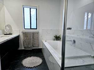 ein weißes Bad mit einer Badewanne, einem Waschbecken und einer Dusche in der Unterkunft Charming on Cormorant in Kialla