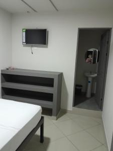 a room with a bathroom with a tv and a toilet at Hotel Singapur in San José