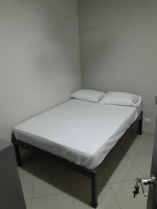 a bed in a room with white sheets and pillows at Hotel Singapur in San José