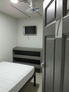 um quarto com uma cama e uma televisão na parede em Hotel Singapur em San José