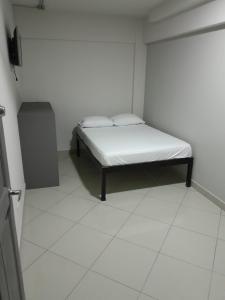 a small white room with a bed in it at Hotel Singapur in San José