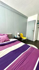 una camera con due letti e una sedia gialla di La Grey Room-Chambre Simple Privée - 700m Stade de France a Saint-Denis