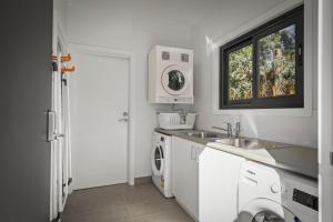 cocina blanca con fregadero y lavadora en Herlihys On Huon - Cabin 1, en Lymington