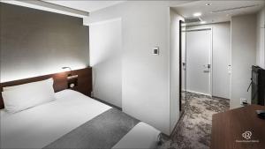 a hotel room with a bed and a door at Daiwa Roynet Hotel Shimbashi in Tokyo