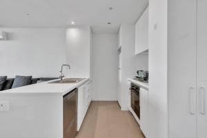 a white kitchen with a sink and a counter at Tranquil 1-Bed Haven with Swimming Pool by CBD in Melbourne