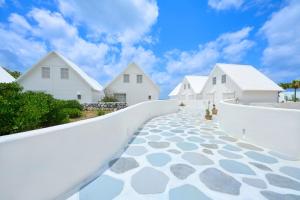 a white house with a white wall and a walkway at Pricia Resort Yoron in Yoron