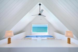 a bedroom with a window in the attic with two lamps at Pricia Resort Yoron in Yoron