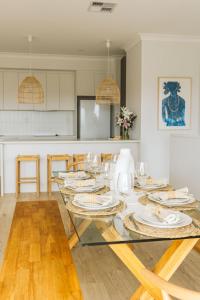 a dining room with a glass table with plates on it at Beyond Beach House in Goolwa South +19 photos