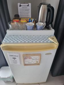 a refrigerator with cups of coffee on top of it at GUESTHOUSE on REGENT Bed & Breakfast in Caloundra +12 photos