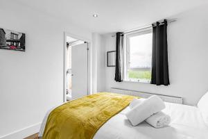 a white bedroom with a bed with a yellow blanket at Pass the Keys Modern Flat near Tower Bridge in London
