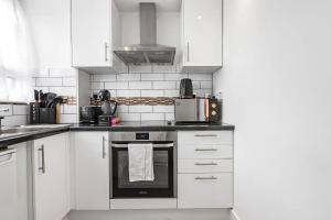 a white kitchen with white cabinets and an oven at Pass the Keys Modern Flat near Tower Bridge in London