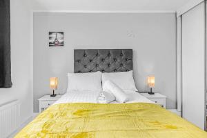 a white bedroom with a large bed with a yellow blanket at Pass the Keys Modern Flat near Tower Bridge in London