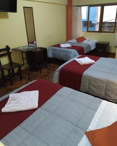 Habitación de hotel con 3 camas y espejo en Hospedaje Del Carmen, en Machu Picchu
