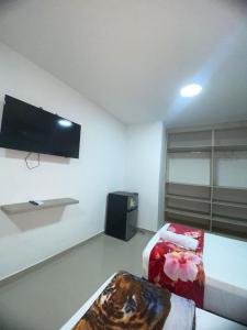a room with two beds and a flat screen tv at Hostal Tamaca Beach in Puerto de Gaira +12 photos