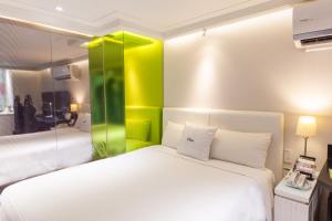 una camera da letto con un letto bianco con accenti verdi di i hotel - Taoyuan a Taoyuan