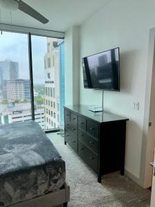 una camera da letto con TV a schermo piatto su un comò di Ruby Retreat - Highrise! Balcony,Pool,City View ad Atlanta