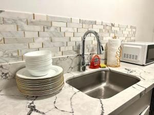 a kitchen counter with a sink and a stack of plates at Your Hollywood Adventure Awaits! in Los Angeles