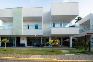 ein weißes Gebäude mit Palmen davor in der Unterkunft Casa em Maragogi/AL in Maragogi