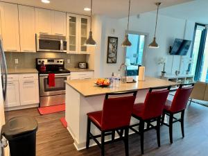 una cucina con isola di cucina con sedie rosse di Ruby Retreat - Highrise! Balcony,Pool,City View ad Atlanta