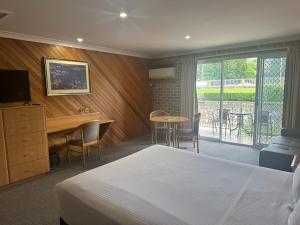 Cette chambre comprend un lit, un bureau et une table. dans l'établissement The Hermitage Motel - Campbelltown, à Campbelltown