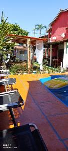 a swimming pool with chairs and a house at Pousada Ray Sol - Centro Arraial d Ajuda in Porto Seguro