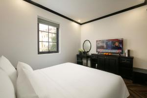 a bedroom with a bed and a flat screen tv at Elegant Boutique Hotel Ha Long in Ha Long