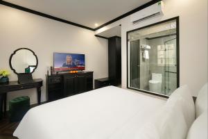 Schlafzimmer mit einem weißen Bett und einem Spiegel in der Unterkunft Elegant Boutique Hotel Ha Long in Hạ Long