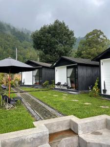 a group of cabins with an umbrella and grass at Ginastro Hom in Bangli