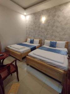1 dormitorio con 2 camas, silla y mesa en Nhà nghỉ Kim Cương, en Rạch Giá